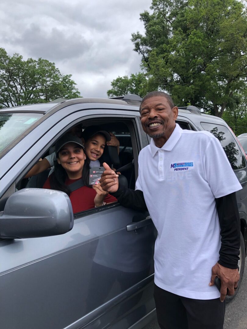 A food recipient family receives a gas gift card from Muggsy at our 2023 Spring Labor of Love