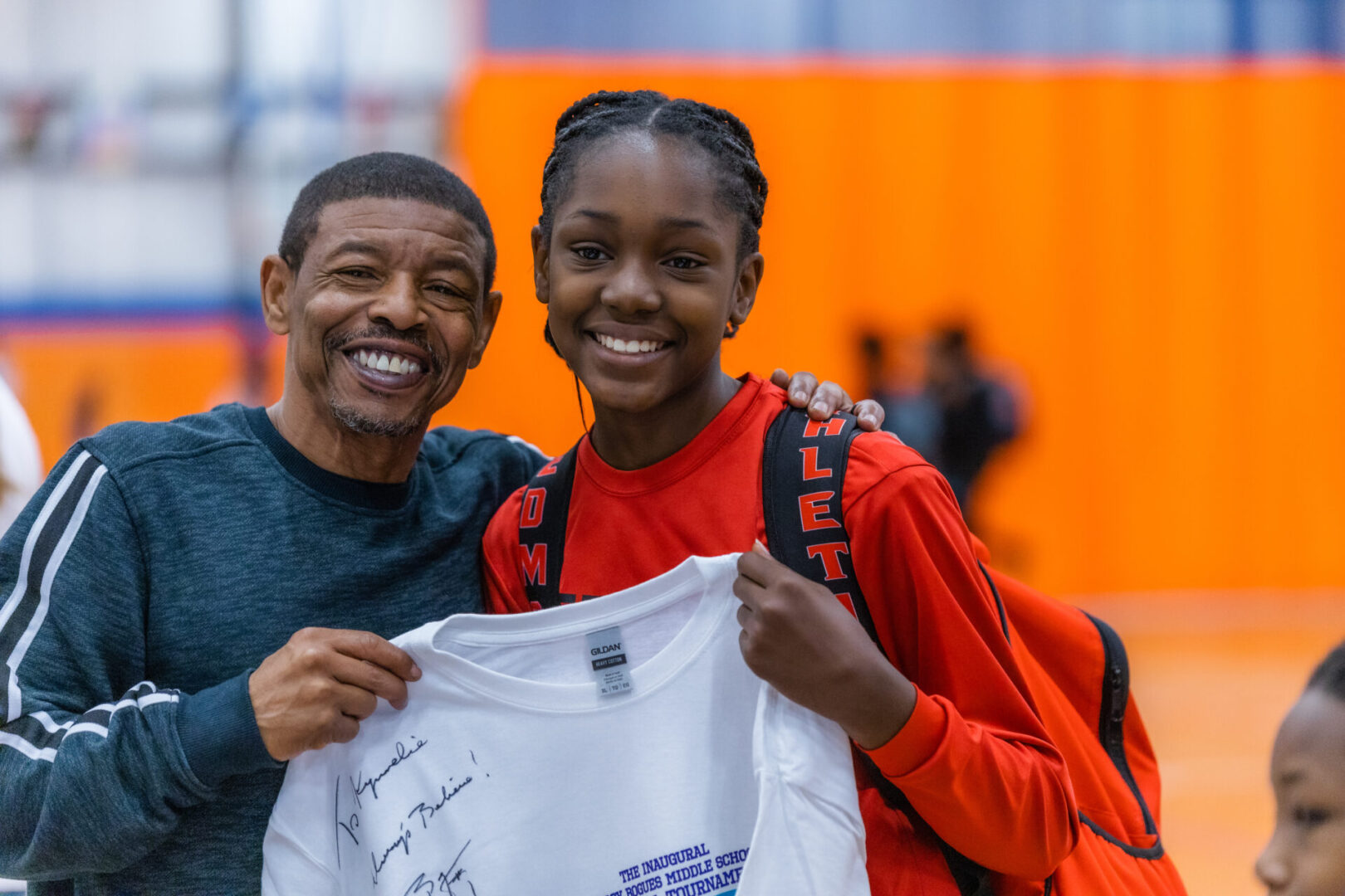 Muggsy autographs tee shirt for player in the 2023 Muggsy Bogues Middle School Basketball Tournament, a signature fundraising event of the MBFF 